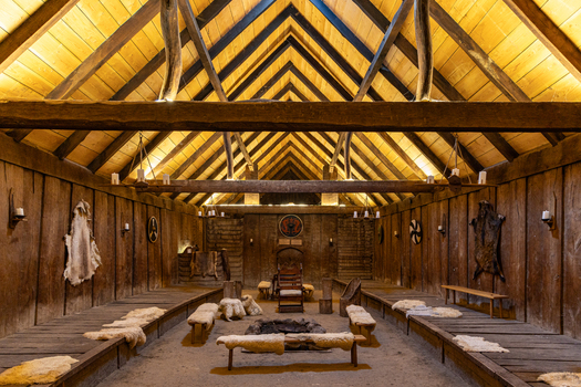View of The Viking Fortress Trelleborg interior with wooden walls fur covered benches and a central fire pit in Slagelse Sjaelland Denmark. View of The Viking Fortress Trelleborg interior with wooden walls fur covered benches and a central fire pit in Slagelse Sjaelland Denmark.