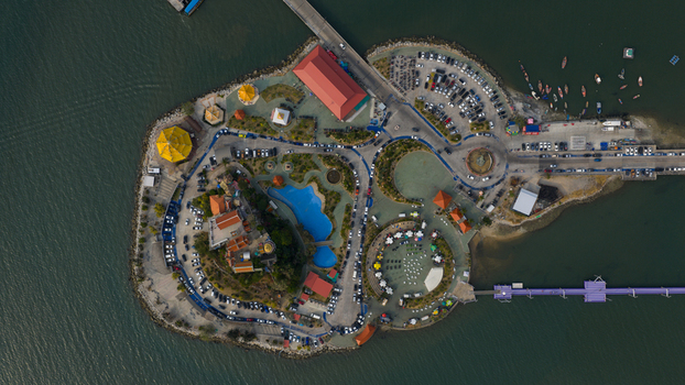 Aerial view of Koh Loi island featuring its temple complex parking areas small park and pedestrian bridge connecting to the mainland in Si Racha Chon Buri Thailand. Aerial view of Koh Loi island featuring its temple complex parking areas small park and pedestrian bridge connecting to the mainland in Si Racha Chon Buri Thailand.