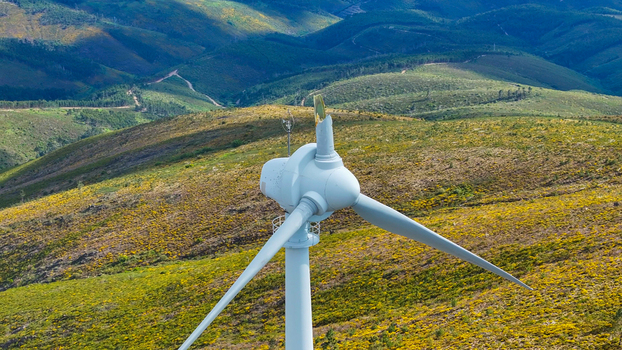 Aerial view of a wind turbine standing on a grassy hillside with rolling hills and vegetation in the background Lisbon Lisbon Portugal. Aerial view of a wind turbine standing on a grassy hillside with rolling hills and vegetation in the background Lisbon Lisbon Portugal.