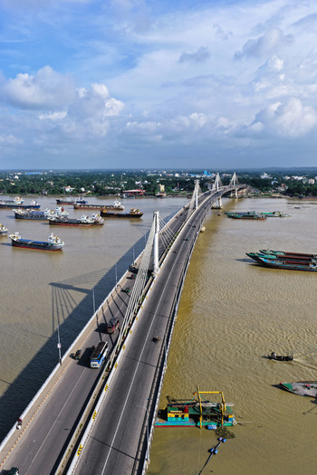 Aerial view of the Shah Amanat Bridge spanning the Karnaphuli River with cargo ships and boats navigating the waterway in Chattogram Chittagong Division Bangladesh.