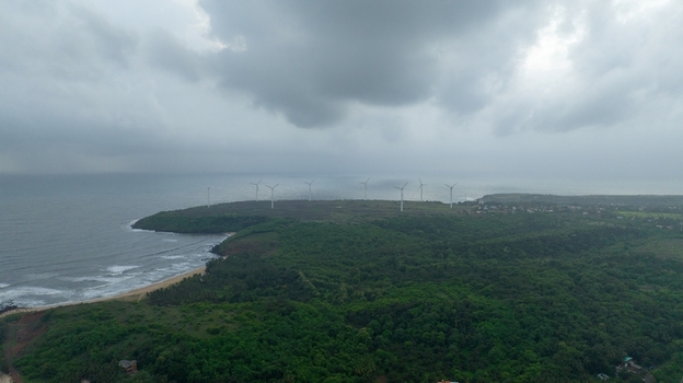 Aerial view of Devgad Windmills situated on a lush green coastal cliff overlooking the Arabian Sea under a dramatic cloudy sky in Devgad Maharashtra India. Aerial view of Devgad Windmills situated on a lush green coastal cliff overlooking the Arabian Sea under a dramatic cloudy sky in Devgad Maharashtra India.