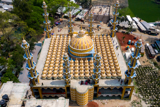 Aerial view of a majestic mosque with gleaming golden domes and towering minarets amidst verdant surroundings and ongoing construction Tangail Dhaka Division Bangladesh. Aerial view of a majestic mosque with gleaming golden domes and towering minarets amidst verdant surroundings and ongoing construction Tangail Dhaka Division Bangladesh.