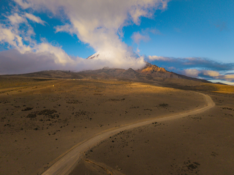 Aerial view of Volcano Chimborazo with a winding dirt road traversing the arid volcanic landscape under a clear blue sky during golden hour in Guano Chimborazo Ecuador. Aerial view of Volcano Chimborazo with a winding dirt road traversing the arid volcanic landscape under a clear blue sky during golden hour in Guano Chimborazo Ecuador.