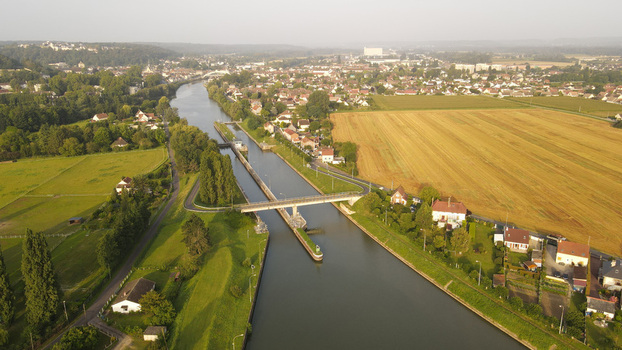 Aerial view of the canal lock and bridge surrounded by fields trees and residential houses in Pontoise Ile de France France. Aerial view of the canal lock and bridge surrounded by fields trees and residential houses in Pontoise Ile de France France.