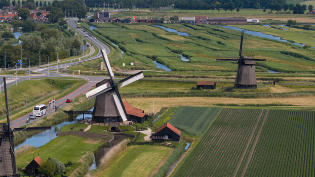 Aerial view of historic windmills in Schermerhorn surrounded by lush green fields irrigation canals and a winding road in Schermerhorn North Holland Netherlands. Aerial view of historic windmills in Schermerhorn surrounded by lush green fields irrigation canals and a winding road in Schermerhorn North Holland Netherlands.