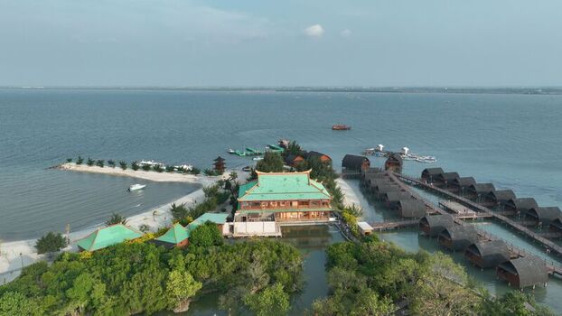 Aerial view of Pulau Lima Resort featuring traditional wooden bungalows over the water a central green roofed building and sandy beaches in Kasemen Banten Indonesia. Aerial view of Pulau Lima Resort featuring traditional wooden bungalows over the water a central green roofed building and sandy beaches in Kasemen Banten Indonesia.