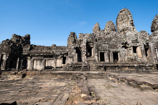 View of Bayon Temple with its iconic stone faces intricate carvings and weathered sandstone blocks under a clear blue sky in Krong Siem Reap Siem Reap Province Cambodia. View of Bayon Temple with its iconic stone faces intricate carvings and weathered sandstone blocks under a clear blue sky in Krong Siem Reap Siem Reap Province Cambodia.
