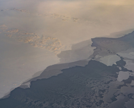 Aerial view of the frozen landscape where the icy expanse meets the dark waters a stark contrast under the muted sky Narsarsuaq Greenland.