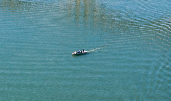 Aerial view of a small salmon fishing boat moving across the calm blue water in Gold Beach Oregon United States.