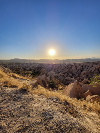 View of the unique rock formations and fairy chimneys under a bright setting sun in Cappadocia Turkiye. View of the unique rock formations and fairy chimneys under a bright setting sun in Cappadocia Turkiye.