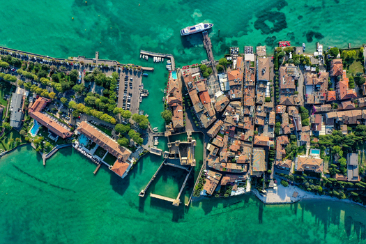 Aerial view of Castello Scaligero di Sirmione the historic fortress and harbor on Lake Garda with turquoise waters and boats in Sirmione Lombardia Italy.