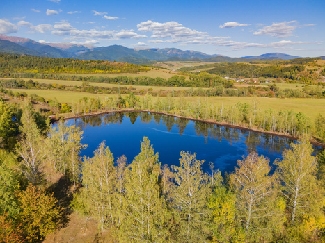 Aerial view of the Gudronove jamy acid tar lagoons surrounded by trees and fields with the Low Tatras mountains in the background in Predajna Banskobystricky kraj Slovakia. Aerial view of the Gudronove jamy acid tar lagoons surrounded by trees and fields with the Low Tatras mountains in the background in Predajna Banskobystricky kraj Slovakia.