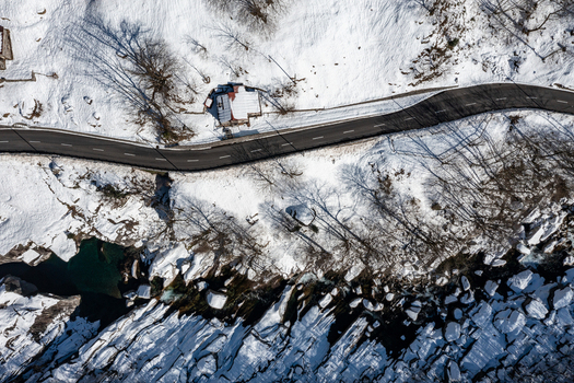 Aerial view of the Valle Verzasca featuring a winding asphalt road through a snow covered landscape with a small house and bare trees Verzasca Ticino Switzerland. Aerial view of the Valle Verzasca featuring a winding asphalt road through a snow covered landscape with a small house and bare trees Verzasca Ticino Switzerland.