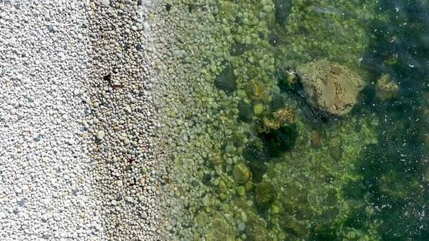 Aerial view of Glenlough Bay pebble beach and clear water Ireland.