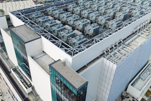 Aerial view of a modern data center facility featuring extensive rooftop cooling units complex HVAC infrastructure and industrial metal framework in the United Kingdom. Aerial view of a modern data center facility featuring extensive rooftop cooling units complex HVAC infrastructure and industrial metal framework in the United Kingdom.