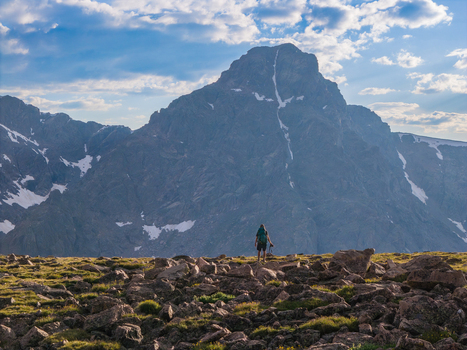 Aerial view of a hiker standing on a rocky ridge with the majestic Mount of the Holy Cross in the background under a blue sky in Vail Colorado United States. Aerial view of a hiker standing on a rocky ridge with the majestic Mount of the Holy Cross in the background under a blue sky in Vail Colorado United States.