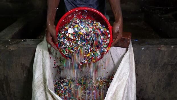 View of a worker pouring shredded plastic into a sack Bangladesh. View of a worker pouring shredded plastic into a sack Bangladesh.