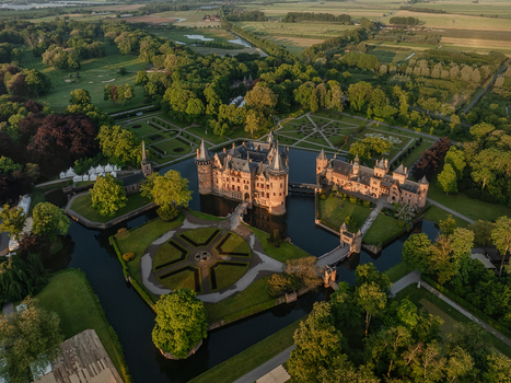 Aerial view of De Haar Castle with its towers and moat surrounded by formal gardens and lush green forests during sunset in Utrecht Utrecht Netherlands. Aerial view of De Haar Castle with its towers and moat surrounded by formal gardens and lush green forests during sunset in Utrecht Utrecht Netherlands.