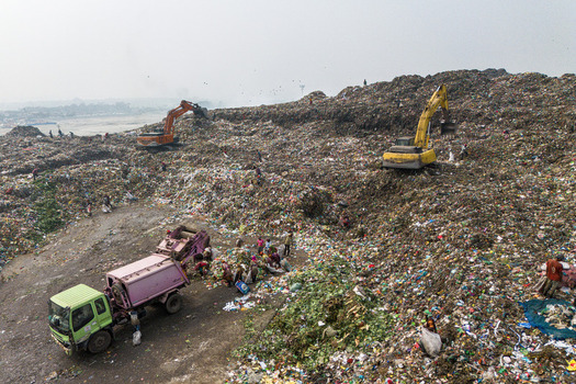 Aminbazar Bangladesh 26 January 2025 Aerial view of the Aminbazar landfill with excavators and people scavenging through massive piles of waste under a hazy sky. Aminbazar Bangladesh 26 January 2025 Aerial view of the Aminbazar landfill with excavators and people scavenging through massive piles of waste under a hazy sky.