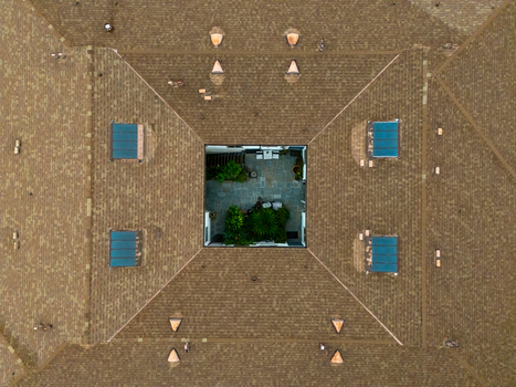 Aerial view of a shingled roof featuring a central courtyard with lush greenery and stone paving in Los Angeles California United States.