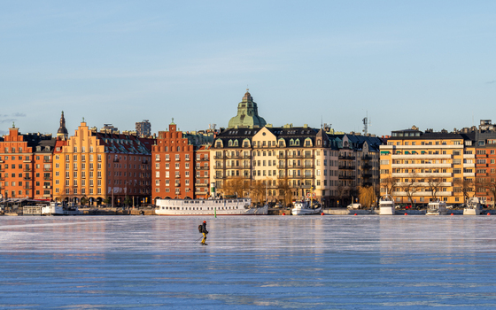 Stockholm Sweden 16 February 2026 View of a person ice skating on the frozen Riddarfjarden with the colorful historic buildings of Soder Malarstrand in the background.
