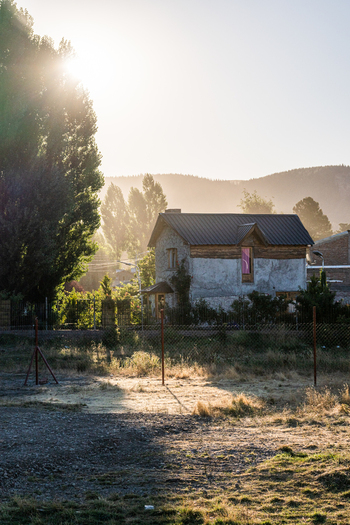 View of a rustic stone and wood house near the Rio Chimehuin during golden hour in Junin de los Andes Neuquen Argentina.