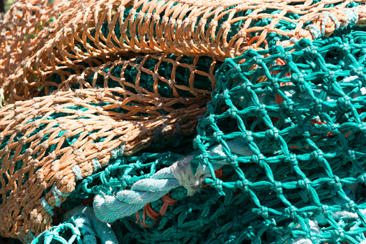 View of tangled orange and green fishing nets with thick ropes piled together in Canada. View of tangled orange and green fishing nets with thick ropes piled together in Canada.