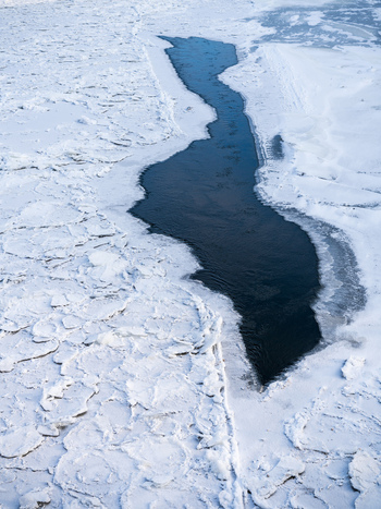 View of a frozen river with floating ice floes and a patch of open dark water in Vilnius Vilnius County Lithuania. View of a frozen river with floating ice floes and a patch of open dark water in Vilnius Vilnius County Lithuania.