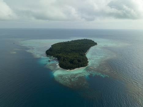 Aerial view of the lush green island surrounded by the turquoise and deep blue ocean waters Menjangan Kecil Island Karimunjawa Central Java Indonesia.