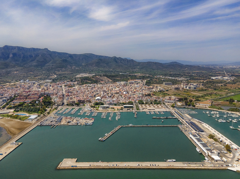 Aerial view of the coastal town and harbor at the Ebro Delta with mountains in the background under a blue sky Catalonia Spain. Aerial view of the coastal town and harbor at the Ebro Delta with mountains in the background under a blue sky Catalonia Spain.
