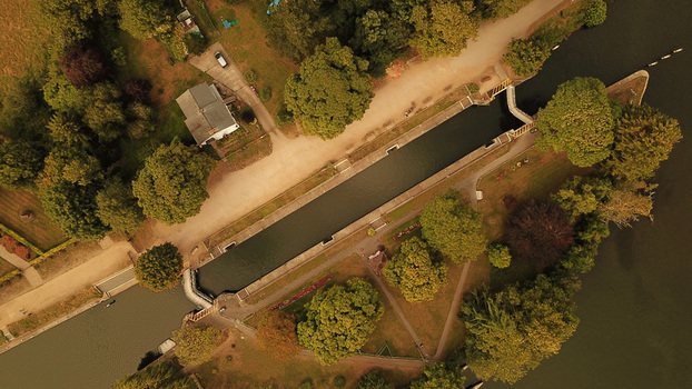 Aerial view of the Thames River lock surrounded by lush green trees grassy banks and a small building in Thames United Kingdom. Aerial view of the Thames River lock surrounded by lush green trees grassy banks and a small building in Thames United Kingdom.