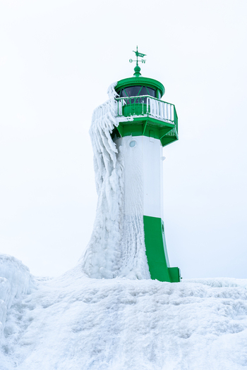 View of the Molenfeuer Sassnitz lighthouse covered in thick layers of ice and snow during a cold winter day in Sassnitz Mecklenburg Vorpommern Germany.