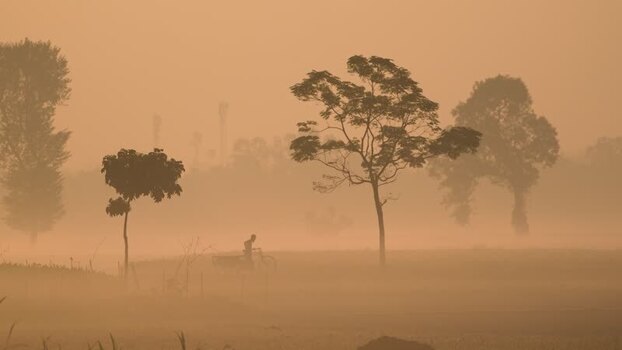 View of a person cycling through thick orange fog Bangladesh. View of a person cycling through thick orange fog Bangladesh.