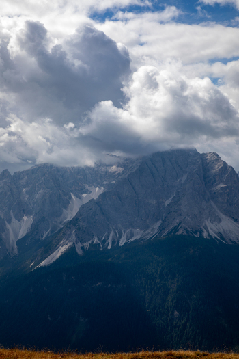 View of the majestic Dolomites mountain peaks partially covered by dramatic clouds above forested slopes in Rocca Pietore Veneto Italy. View of the majestic Dolomites mountain peaks partially covered by dramatic clouds above forested slopes in Rocca Pietore Veneto Italy.