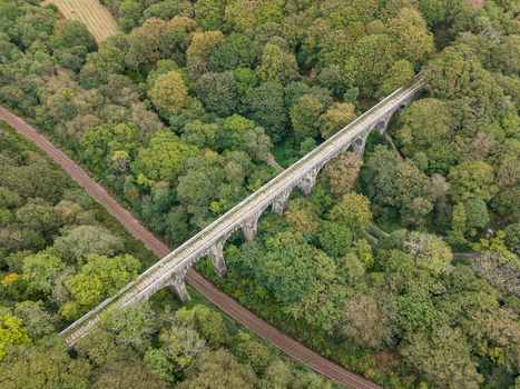 Aerial view of the historic Treffry Viaduct surrounded by dense woodland and lush greenery in the Luxulyan Valley Luxulyan Cornwall United Kingdom.