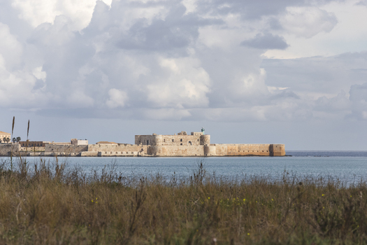 View of the historic Castello Maniace fortress on the coast under a cloudy sky Syracuse Sicily Italy.