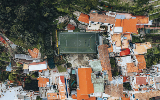 Aerial view of a verdant football field nestled between rustic buildings with terracotta roofs and a lush green hillside Positano Campania Italy. Aerial view of a verdant football field nestled between rustic buildings with terracotta roofs and a lush green hillside Positano Campania Italy.
