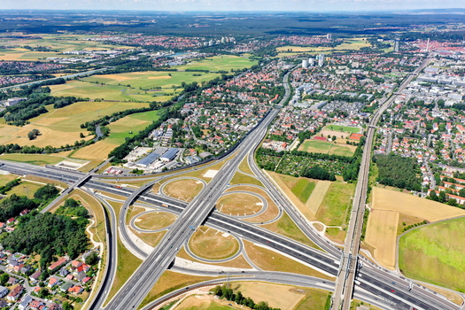 Aerial view of the A73 highway interchange with cloverleaf ramps surrounding green fields and residential neighborhoods in Nurnberg Bayern Germany. Aerial view of the A73 highway interchange with cloverleaf ramps surrounding green fields and residential neighborhoods in Nurnberg Bayern Germany.