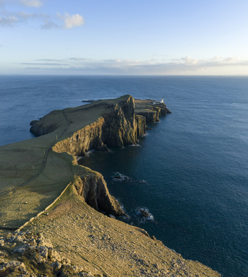 Aerial view of Neist Point Lighthouse perched on dramatic rocky cliffs overlooking the blue Atlantic Ocean during golden hour Isle of Skye Scotland United Kingdom. Aerial view of Neist Point Lighthouse perched on dramatic rocky cliffs overlooking the blue Atlantic Ocean during golden hour Isle of Skye Scotland United Kingdom.