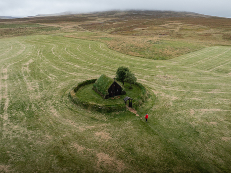 Aerial view of the turf roofed church a verdant jewel nestled in a sea of green fields under a misty sky Hofs&oacute;s Skagafj&ouml;r&eth;ur Iceland.