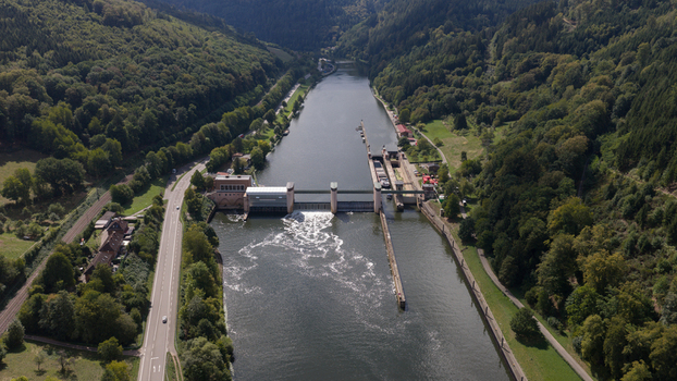 Aerial view of the Neckar Staustufe und Schleuse Rockenau on the Neckar river surrounded by lush forests and infrastructure in Eberbach Baden Wurttemberg Germany.