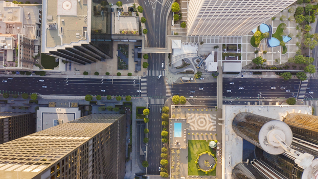 Aerial view of a busy city intersection with modern skyscrapers office buildings landscaped plazas and traffic flowing on urban streets in Los Angeles California United States.
