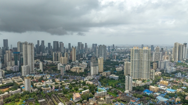 Aerial view of the dense urban skyline of Mumbai with high rise residential towers sprawling neighborhoods and a cloudy sky over the city in Mumbai Maharashtra India.