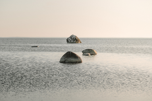 View of large glacial boulders resting in the calm shallow waters off the coast of Vormsi in Laane County Estonia.