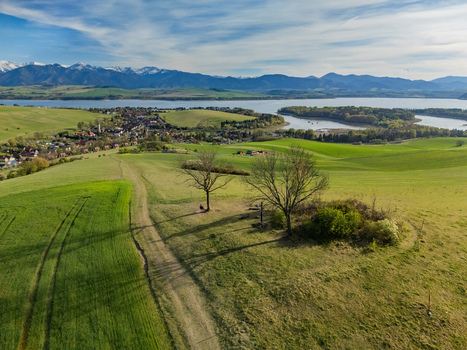 Aerial view of a dirt path and trees overlooking the village the Liptovska Mara reservoir and the snow capped Tatra Mountains in Liptovsky Trnovec Zilina Region Slovakia.