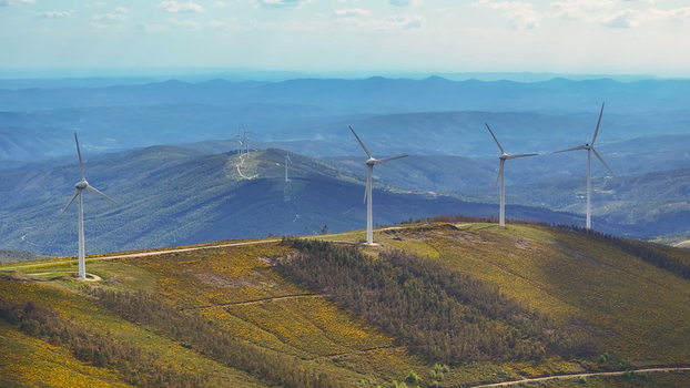 Aerial view of wind turbines on a grassy mountain ridge with rolling hills and a clear blue sky in Lisbon Lisbon Portugal. Aerial view of wind turbines on a grassy mountain ridge with rolling hills and a clear blue sky in Lisbon Lisbon Portugal.