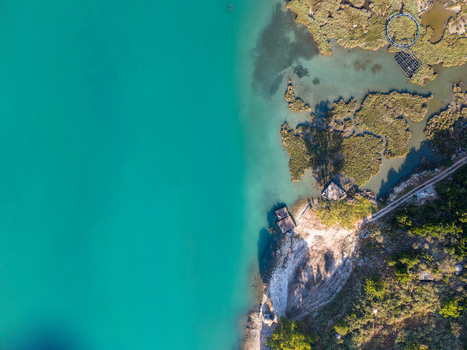 Aerial view of Kanali i Vivarit with its turquoise water meeting the marshy shoreline and green vegetation in Vrine Vlore County Albania. Aerial view of Kanali i Vivarit with its turquoise water meeting the marshy shoreline and green vegetation in Vrine Vlore County Albania.