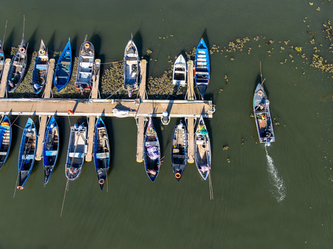 Aerial view of boats moored at the pier reflecting in the dark water Porta de Abrigo da Torreira Aveiro Portugal. Aerial view of boats moored at the pier reflecting in the dark water Porta de Abrigo da Torreira Aveiro Portugal.