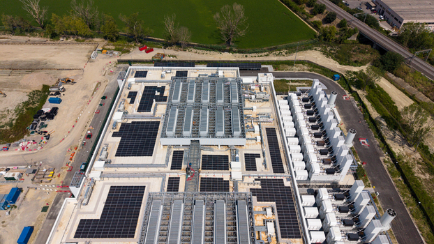 Aerial view of a modern industrial facility featuring extensive rooftop solar panel arrays cooling units and surrounding infrastructure in Milan Lombardy Italy.