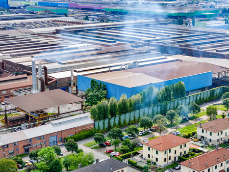 Aerial view of the large industrial complex and factory buildings with smoking chimneys and green trees in Dalmine Lombardy Italy. Aerial view of the large industrial complex and factory buildings with smoking chimneys and green trees in Dalmine Lombardy Italy.